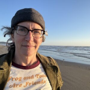 Person with glasses and beanie at beach